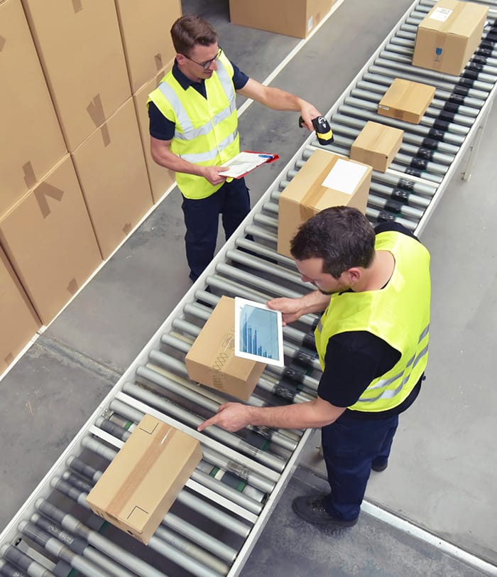 Warehouse workers processing packages on assembly line